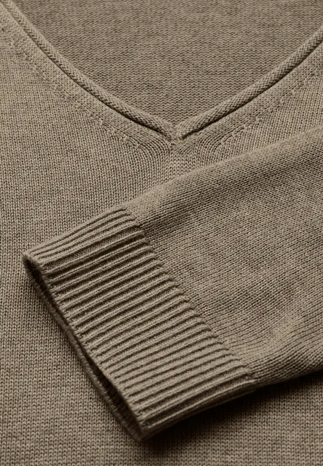 Nahaufnahme eines beigen Pullovers mit V-Ausschnitt.